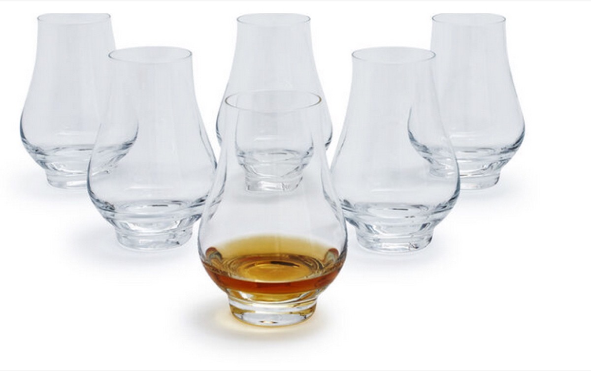 set of six clear glasses, one with whiskey in it