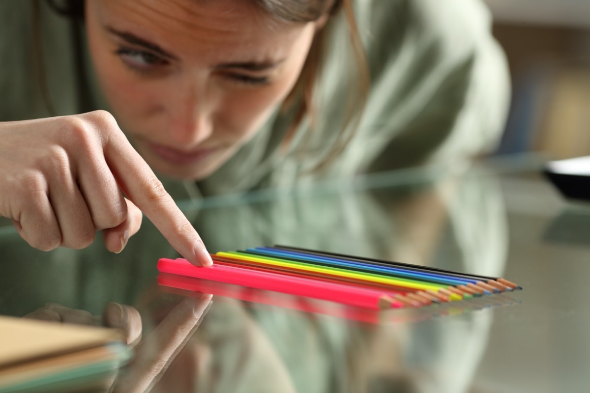 Woman aligning up pencils accurately on a glass table