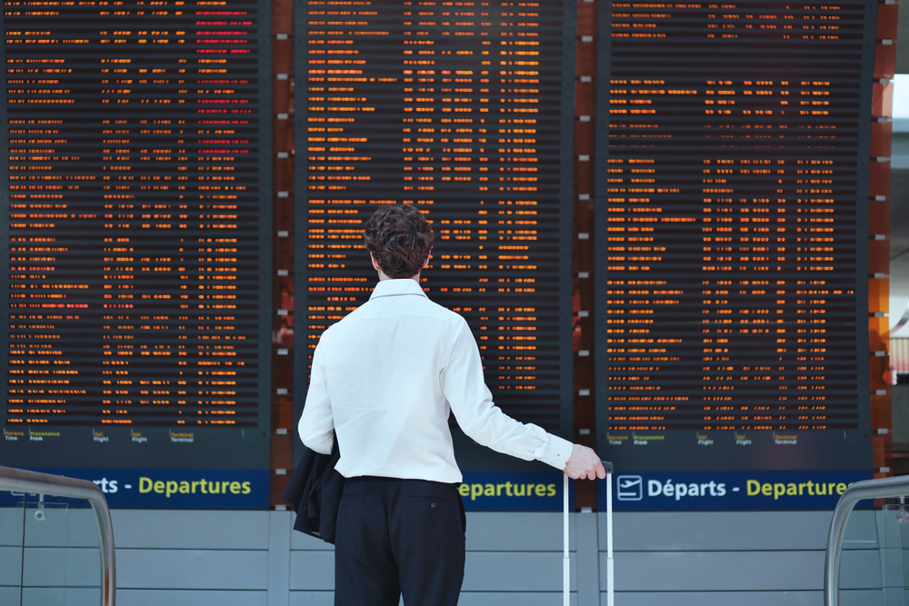 A man looking at the arrivals and departures board in an airport