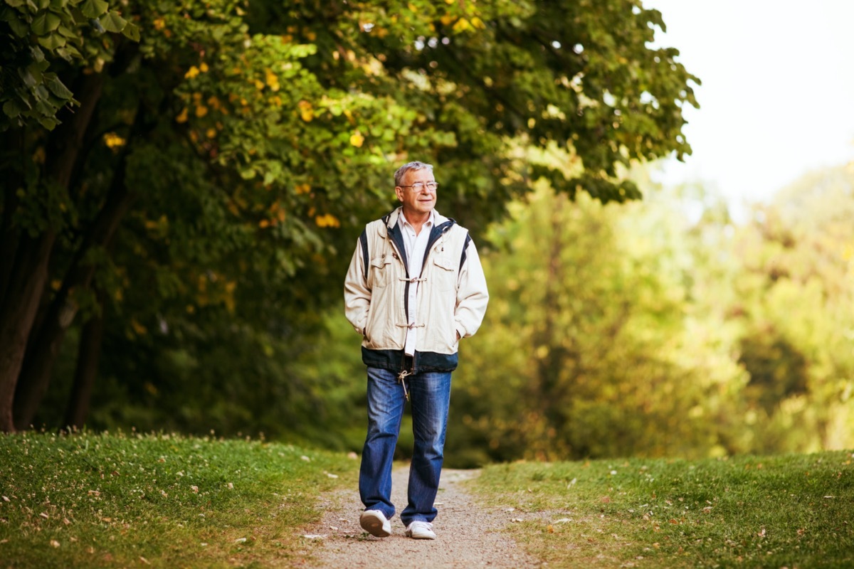 Happy senior man walking and relaxing in park