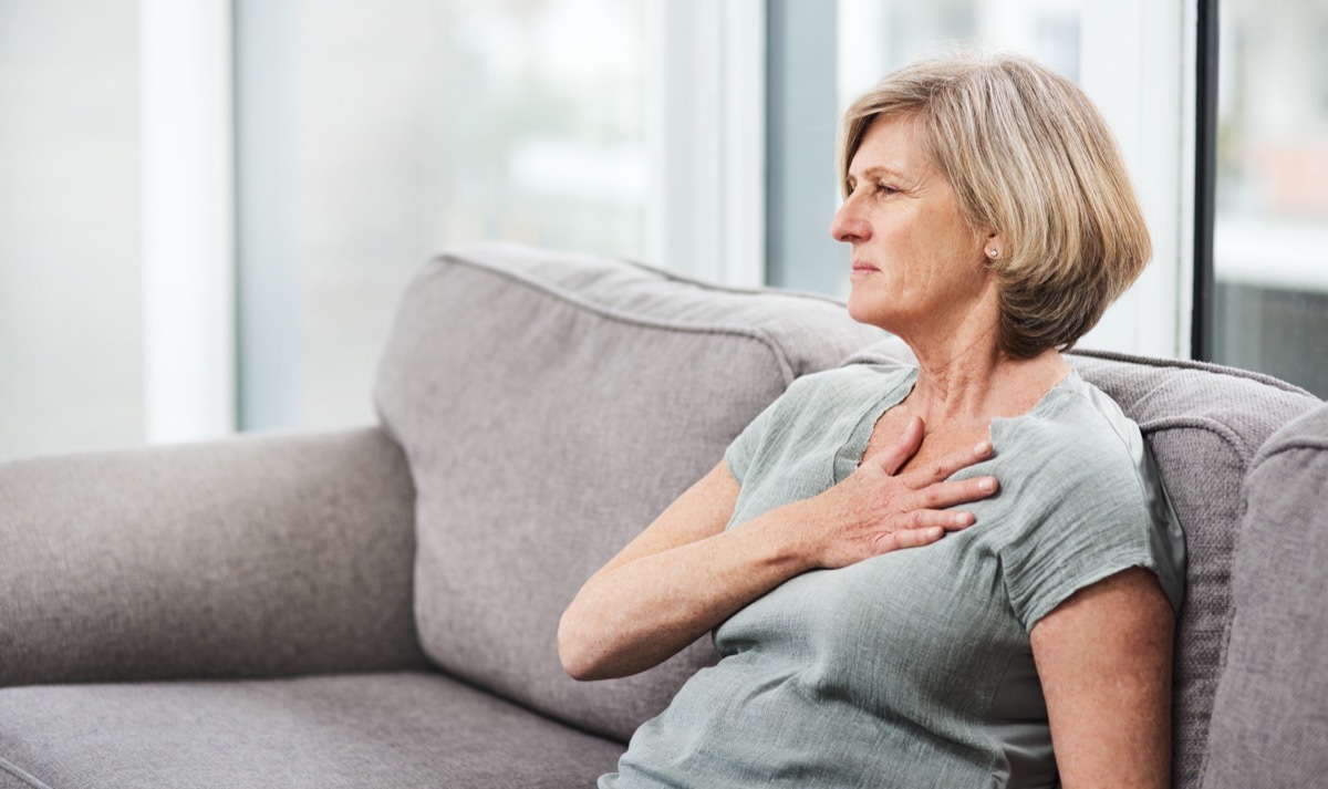 Shot of a senior woman suffering from chest pain while sitting on the sofa at home