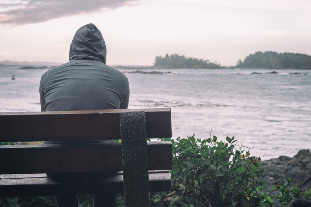 man sitting on a bench looking out on the ocean