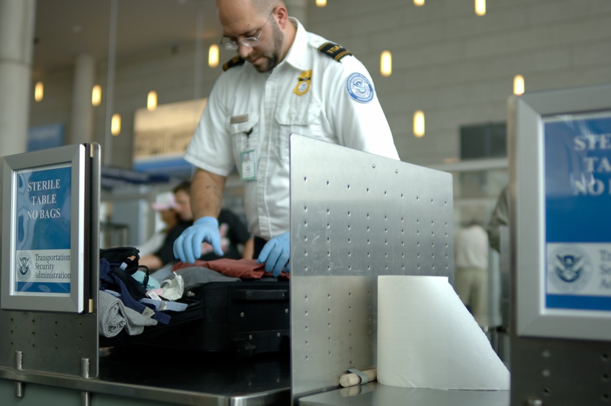 TSA agent searching through someone's luggage at the airport