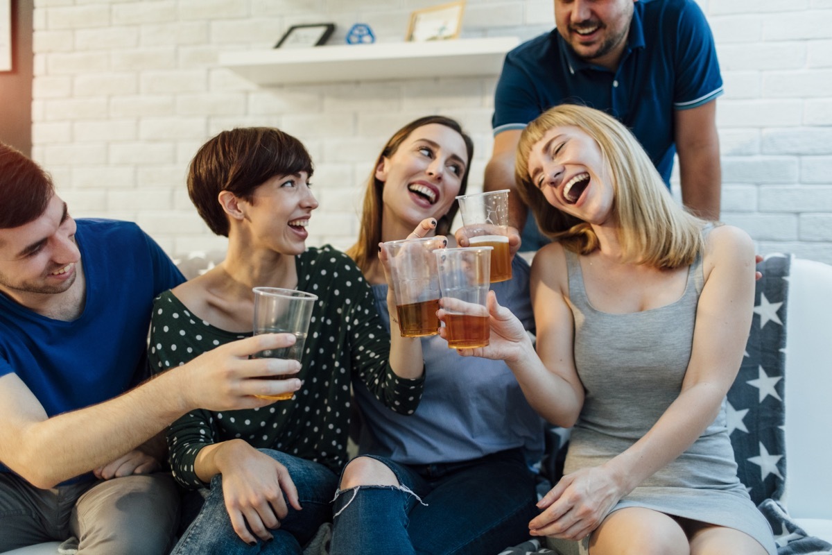 Young people having fun at home party. Toasting with beer and enjoying the party