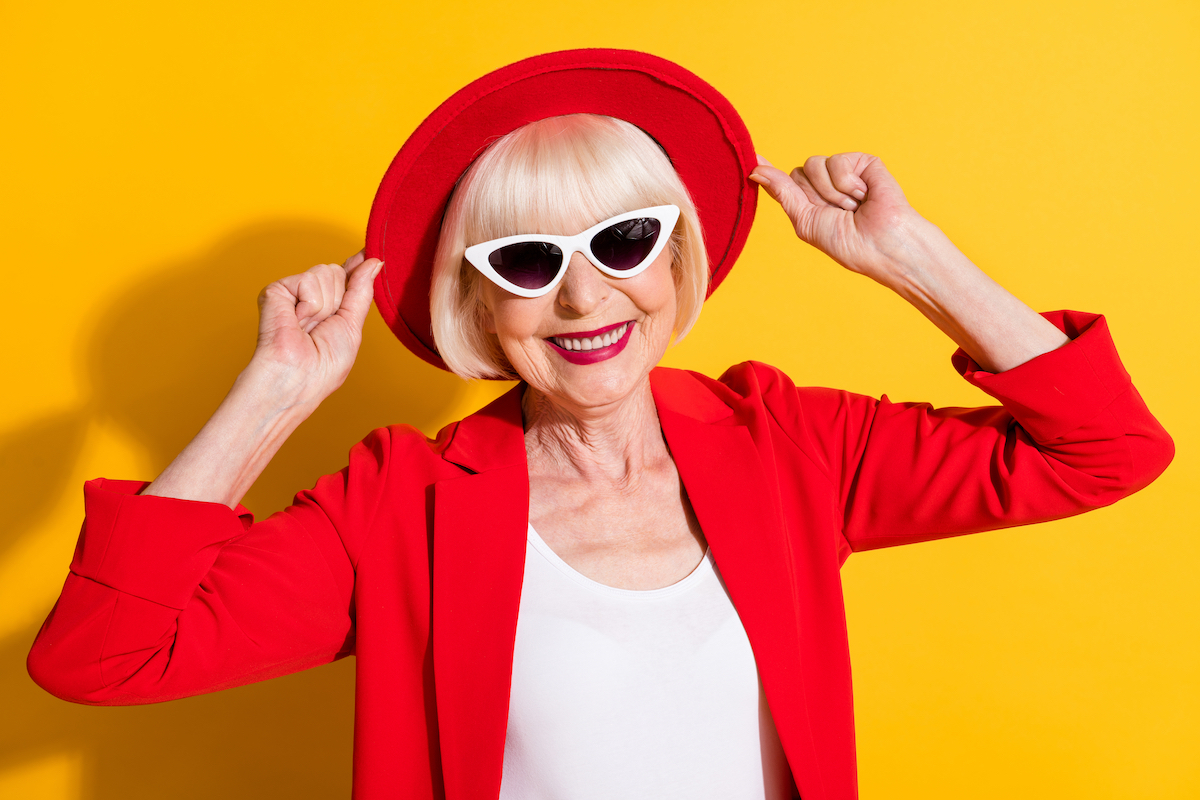 Photo portrait of happy senior lady wearing sunglass red hat smiling in blazer isolated on bright yellow color background