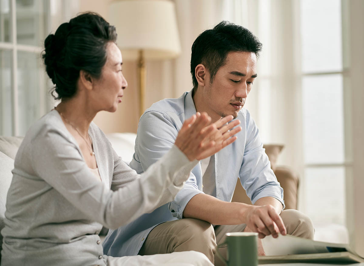 Mother and adult son talking on couch