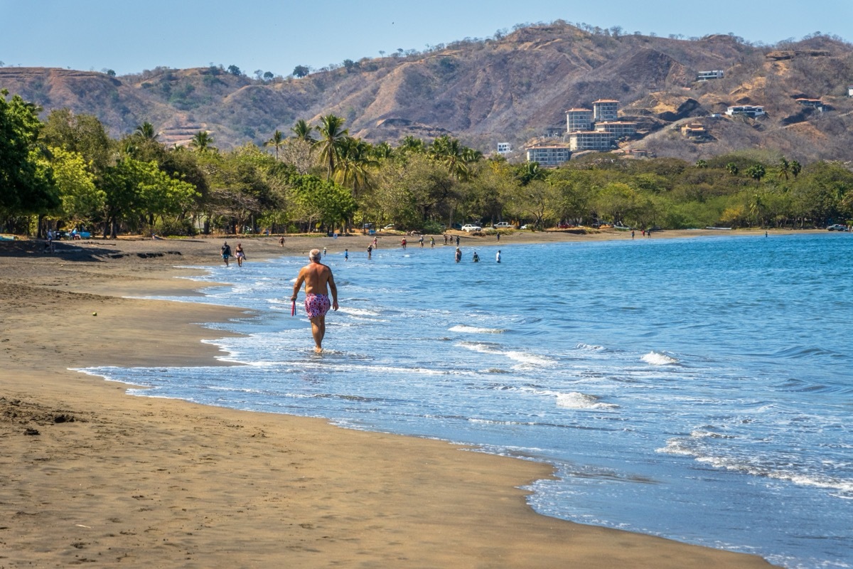 retired man walking along the beach in costa rica