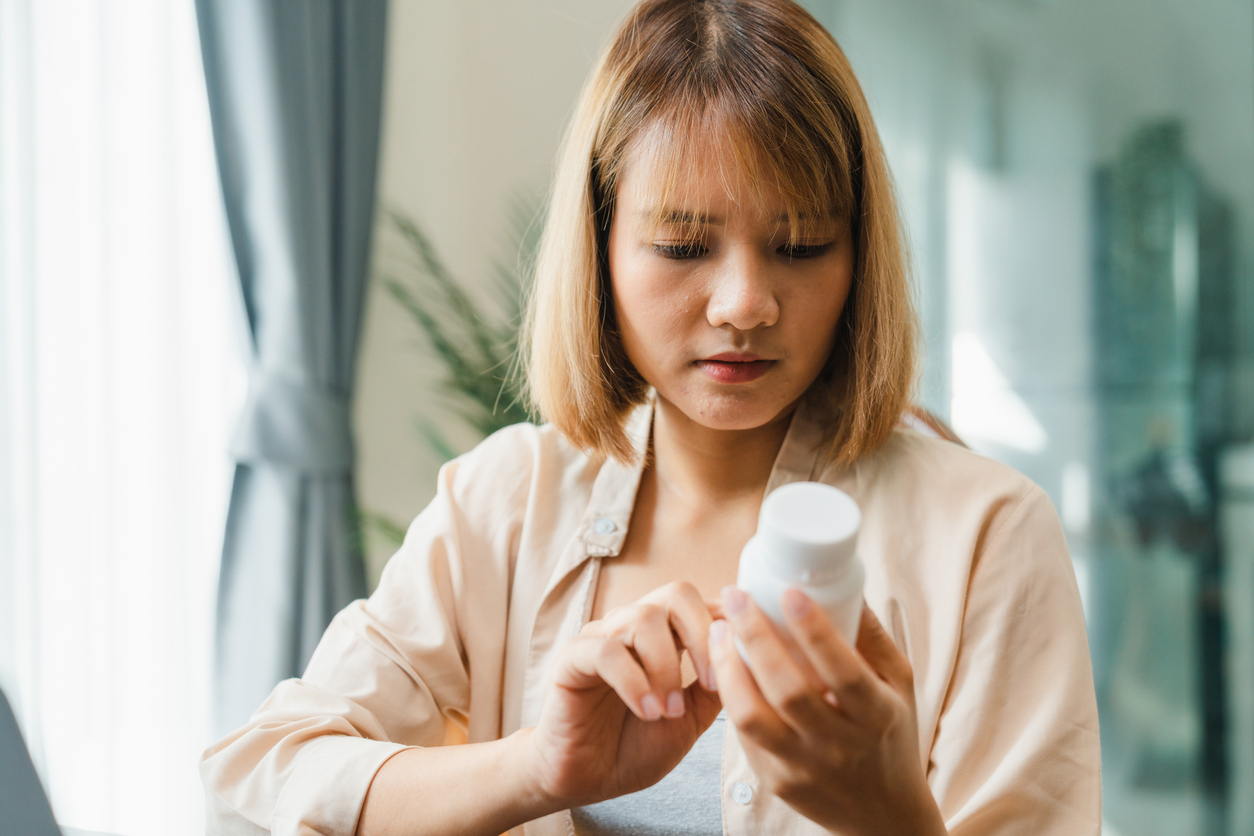 A woman looking at a medication bottle in her hand