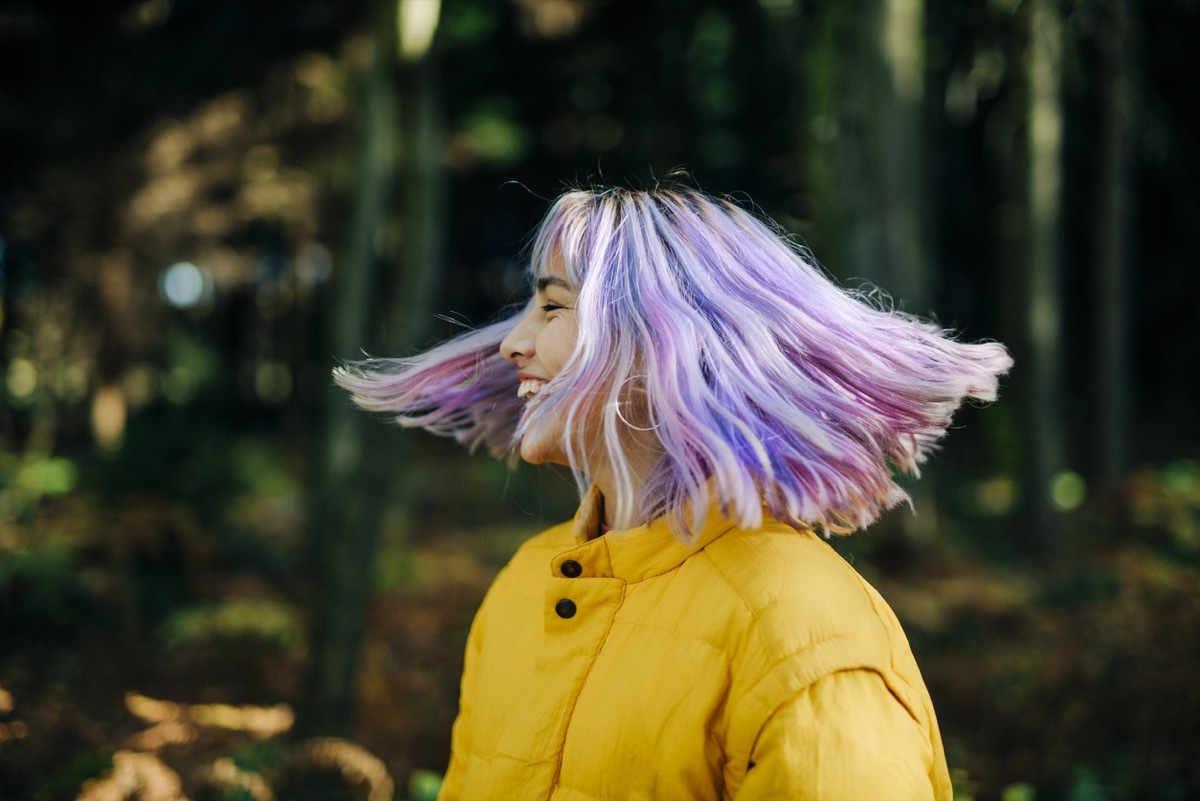 Portrait of confident, young, modern teenage girl with pink, blue hair in nature forest, Germany