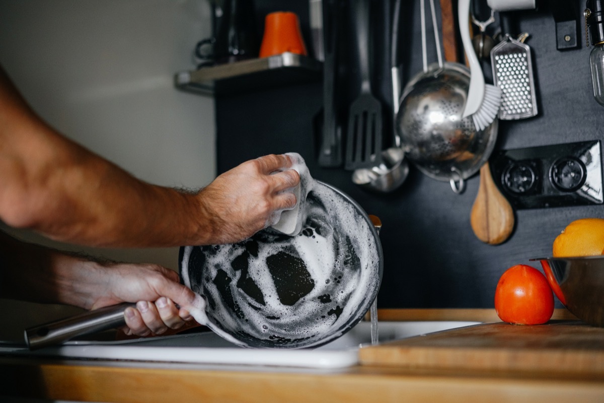 man hand-washing a cast iron pan