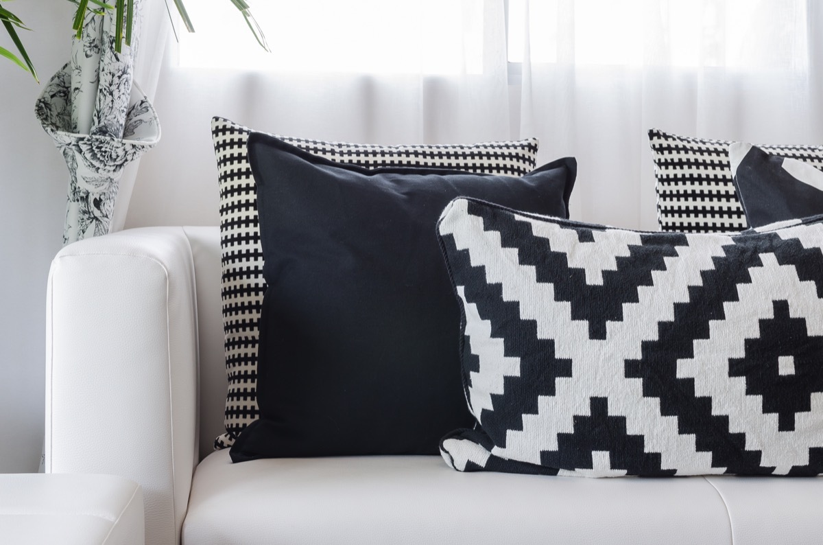 Multiple different black and white patterned pillows resting on a white couch