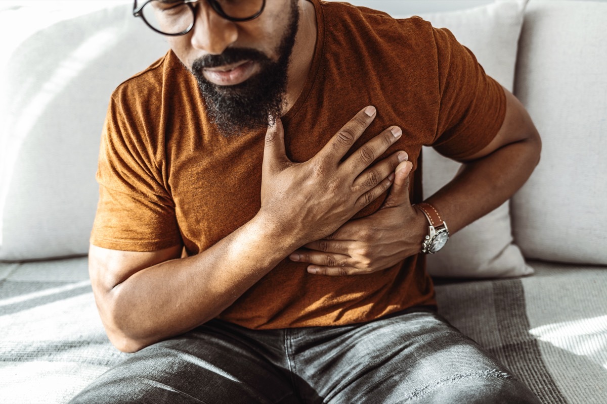 man holding his chest in pain indoors.