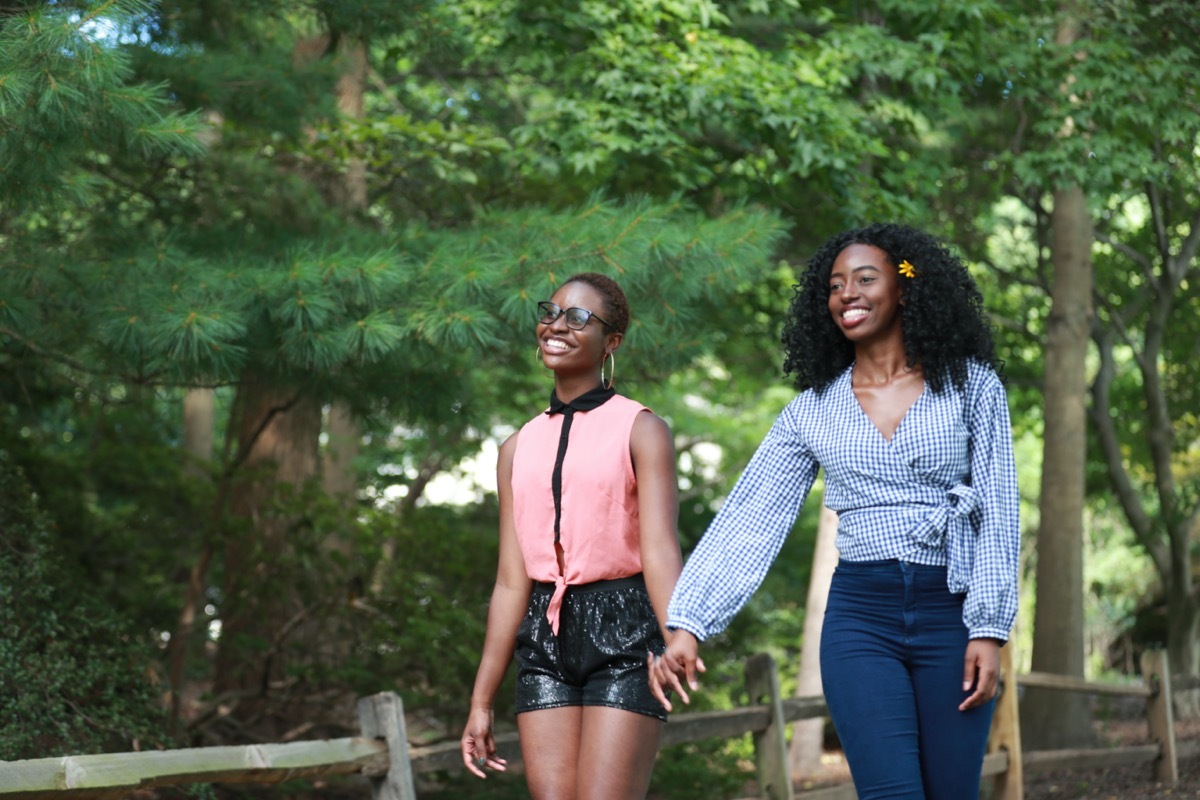 Two young women holding hands and walking in park