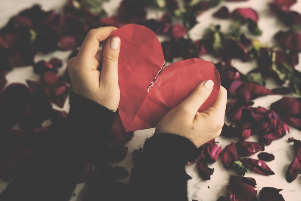 hands holding a ripped heart paper