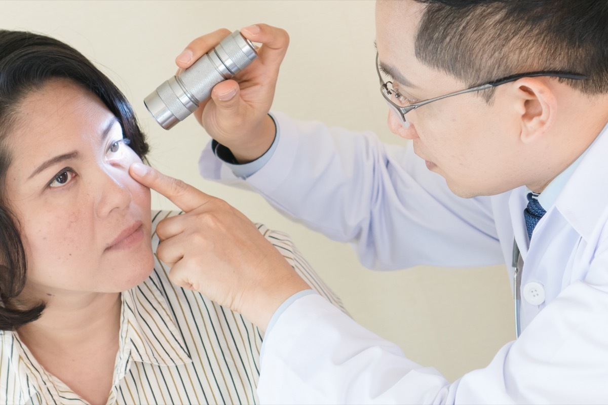 asian doctor examining woman's eye with flashlight