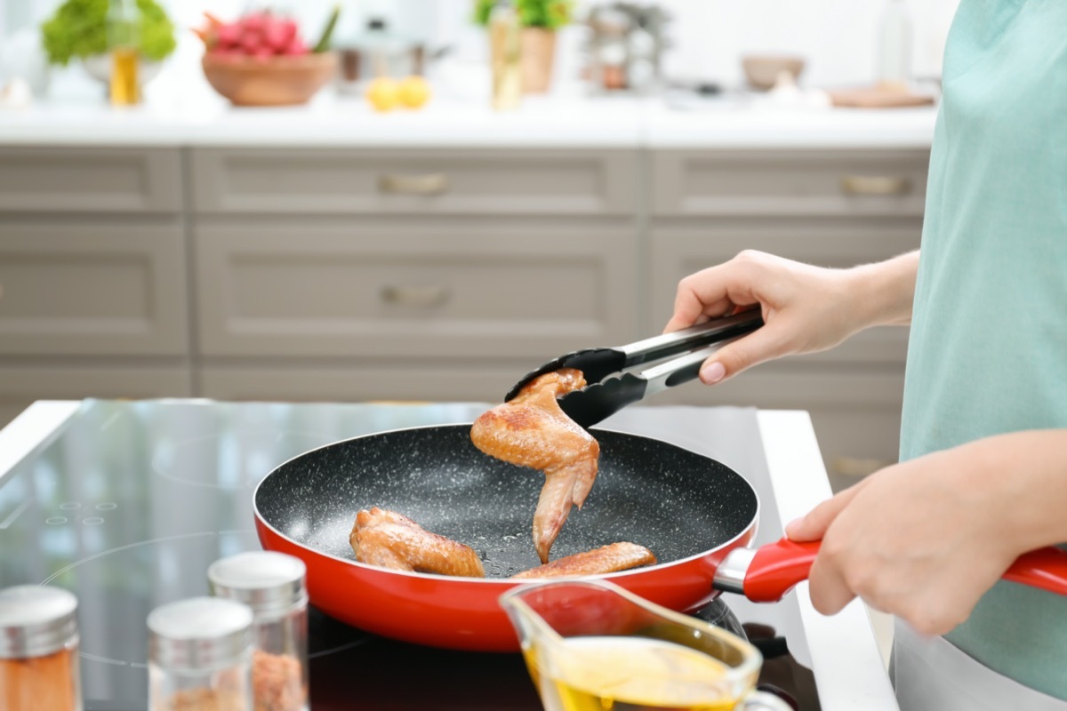 white woman cooking chicken in pan