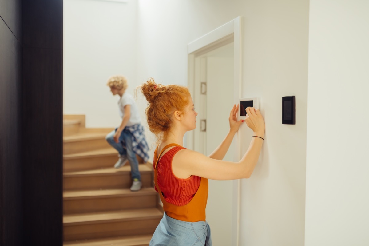 Smart house. Nice joyful woman looking at the sensory panel while pressing it