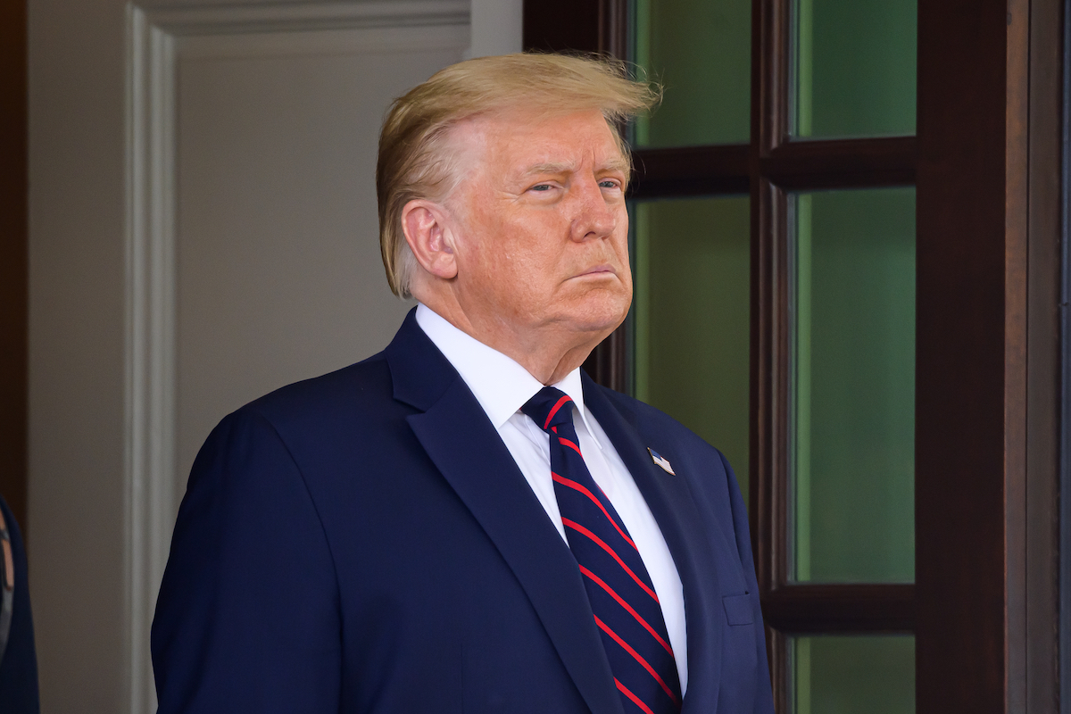 donald trump looks serious in navy blue suit, white shirt, and navy and red tie