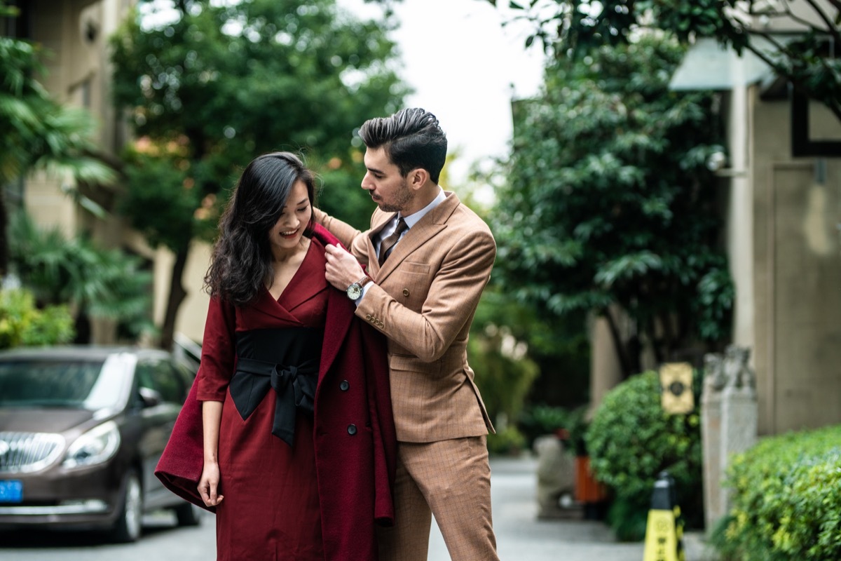 man helping woman put on her coat in the middle of the road