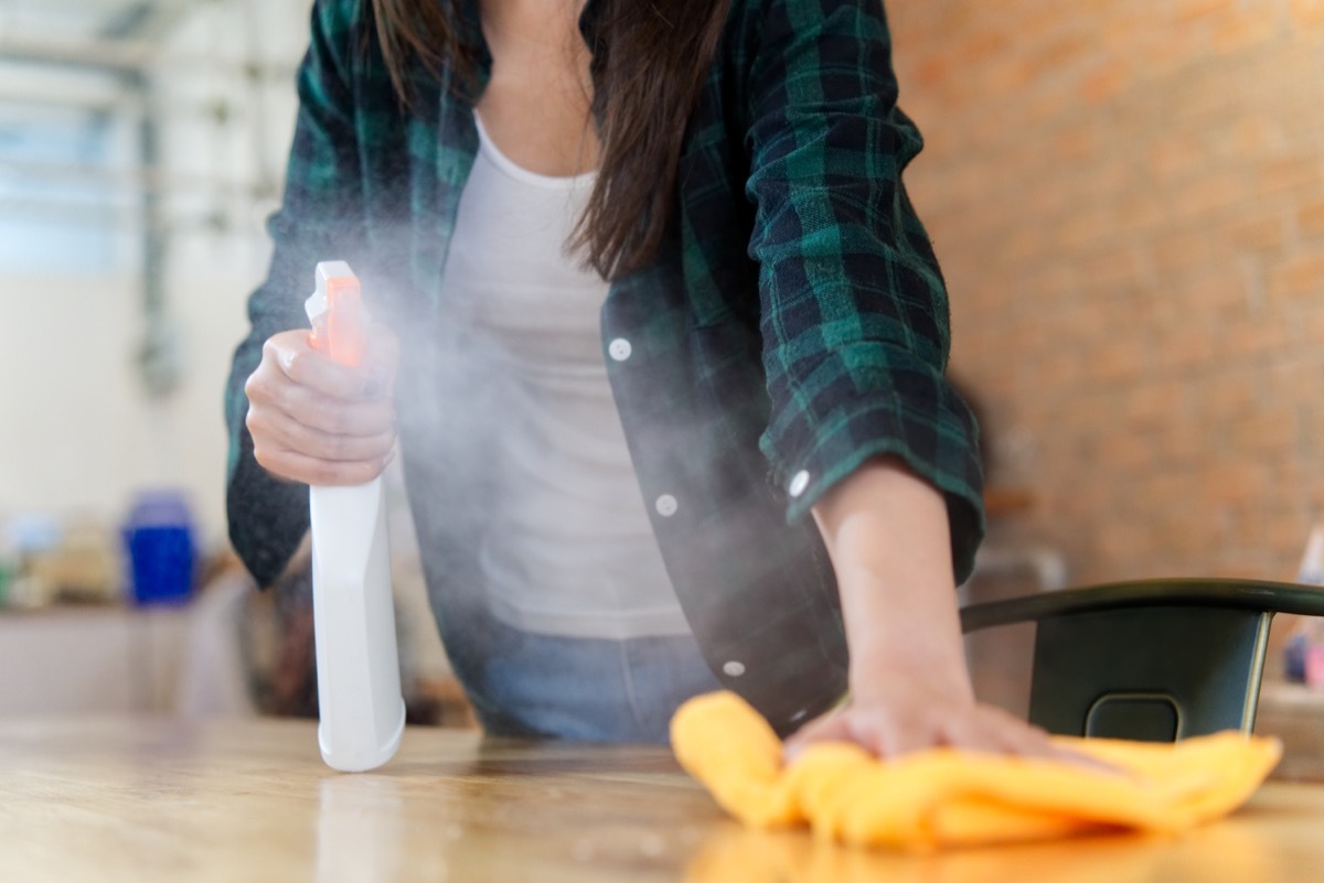 Woman spraying and dusting with microfiber cloth