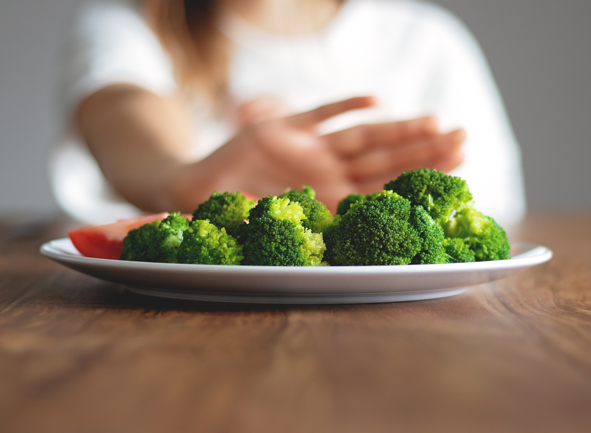 Woman pushing plate of vegetables away from herself because she is skipping a meal