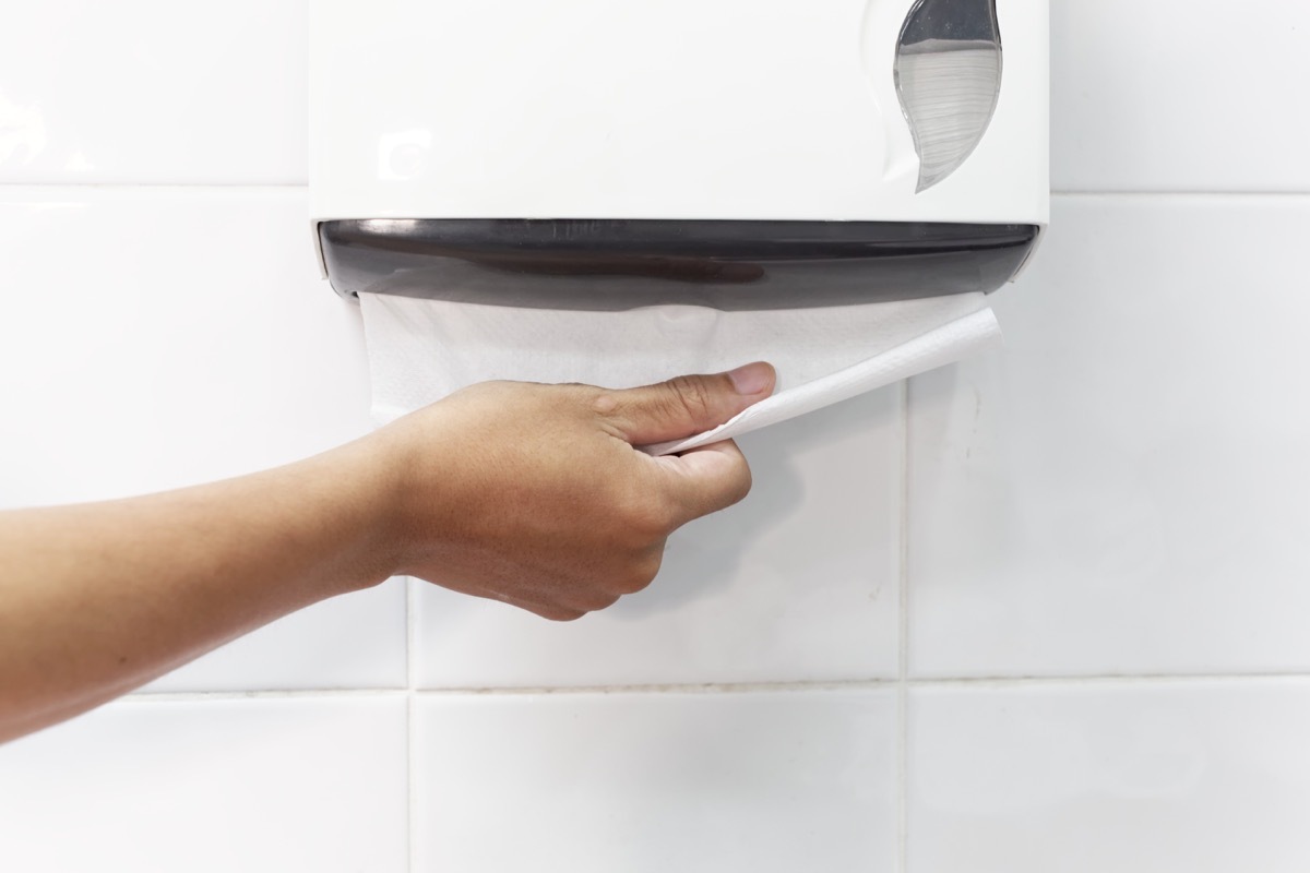 Person using a paper towel dispenser classroom surfaces germs