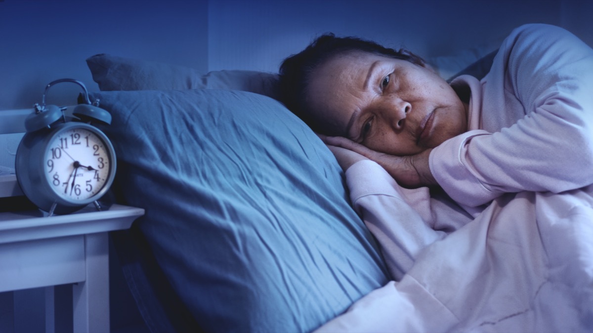 senior woman having sleep disorder, sitting in bed look sad