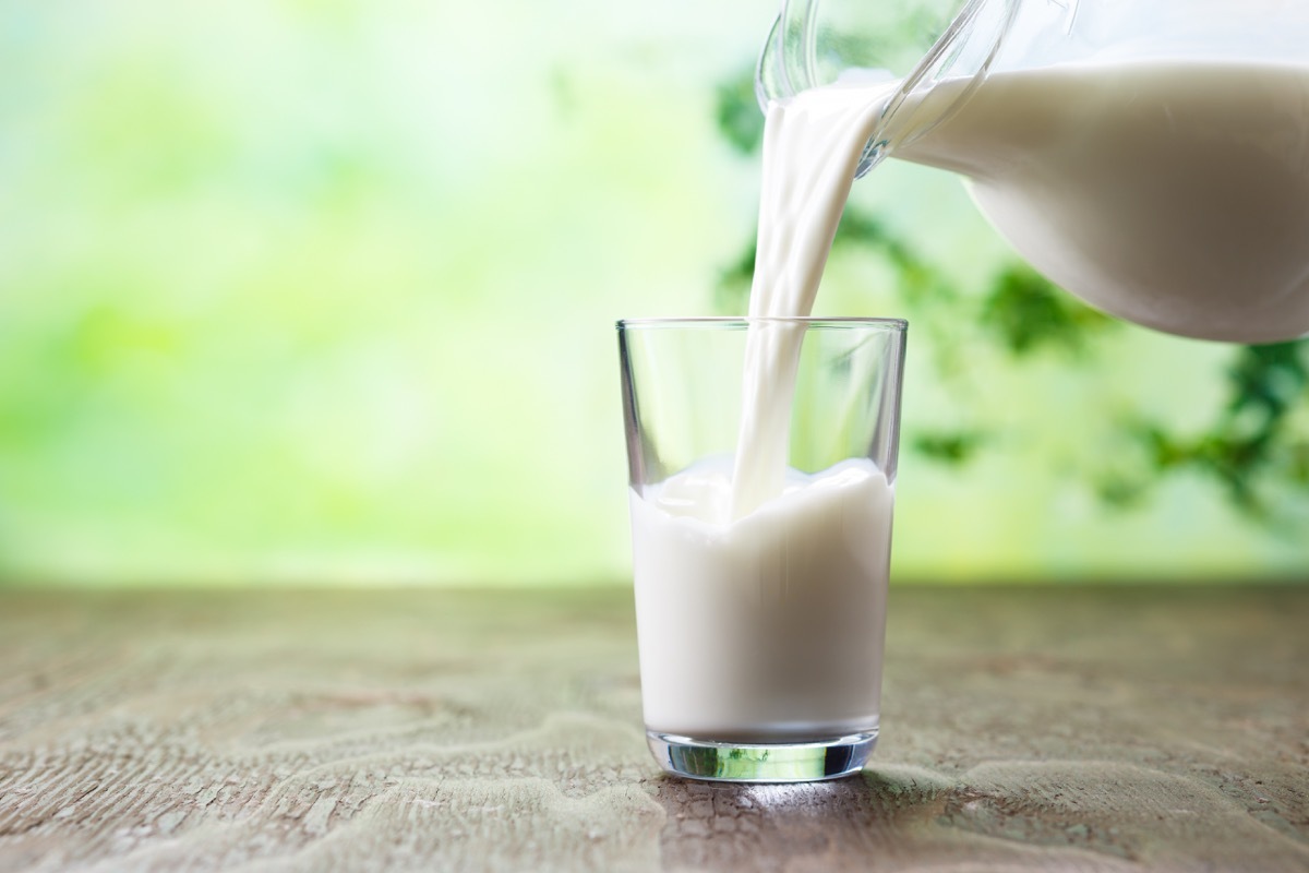 jar pouring glass of milk into cup