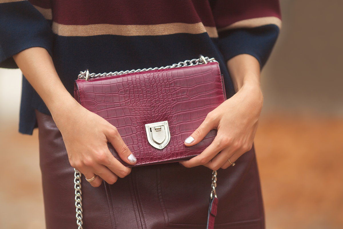 Woman holding fashion red bag in stylish clothes outdoor