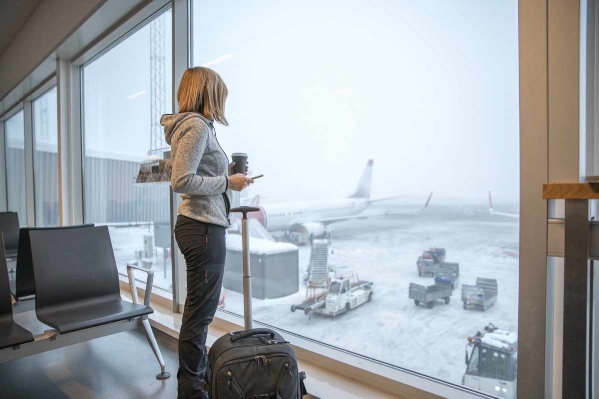 Woman standing close to window with luggage at airport