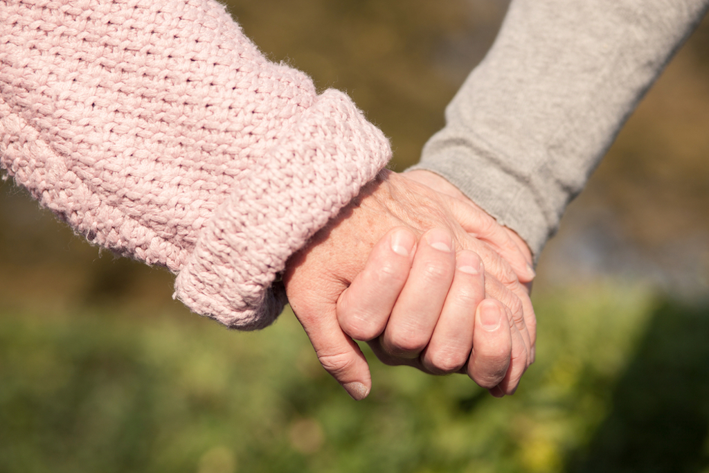 elderly couple holding hands