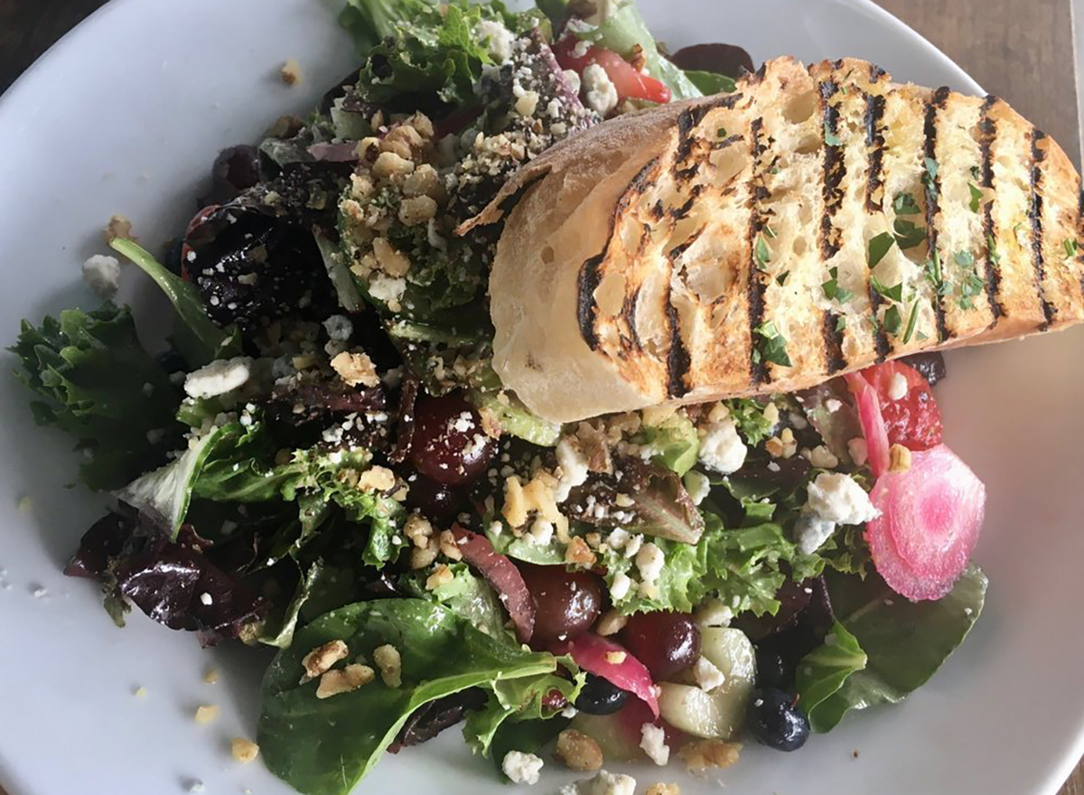 chopped green salad topped with bread and pickled vegetables