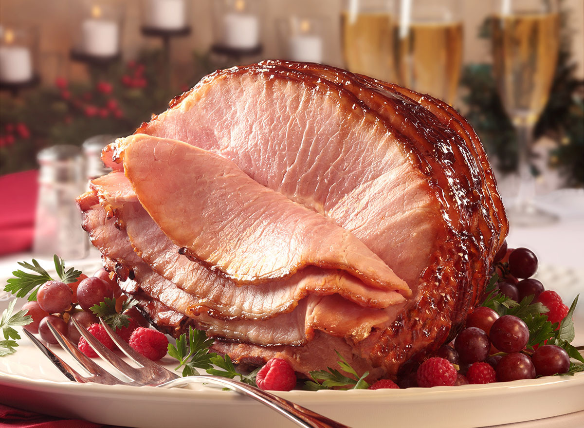 glazed spiral ham on white platter with cranberries