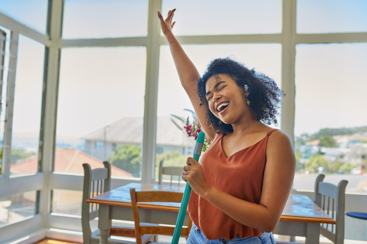 girl singing karaoke into broom handle