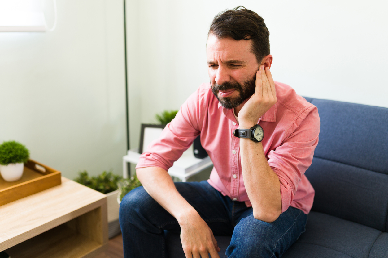 Man sitting and touching at his ear. 