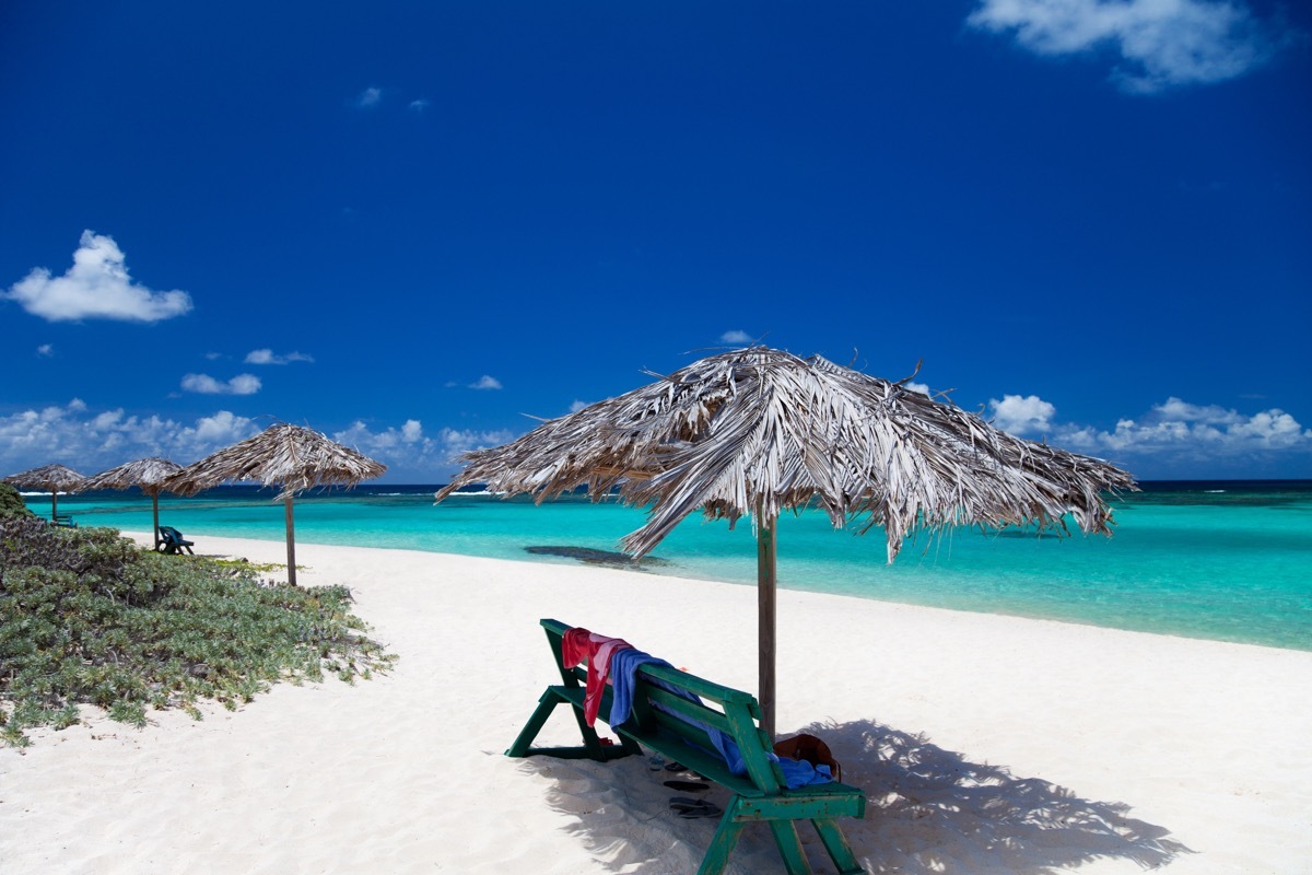 benches under cabana umbrellas on a white sand beach in Anegada, British Virgin Islands