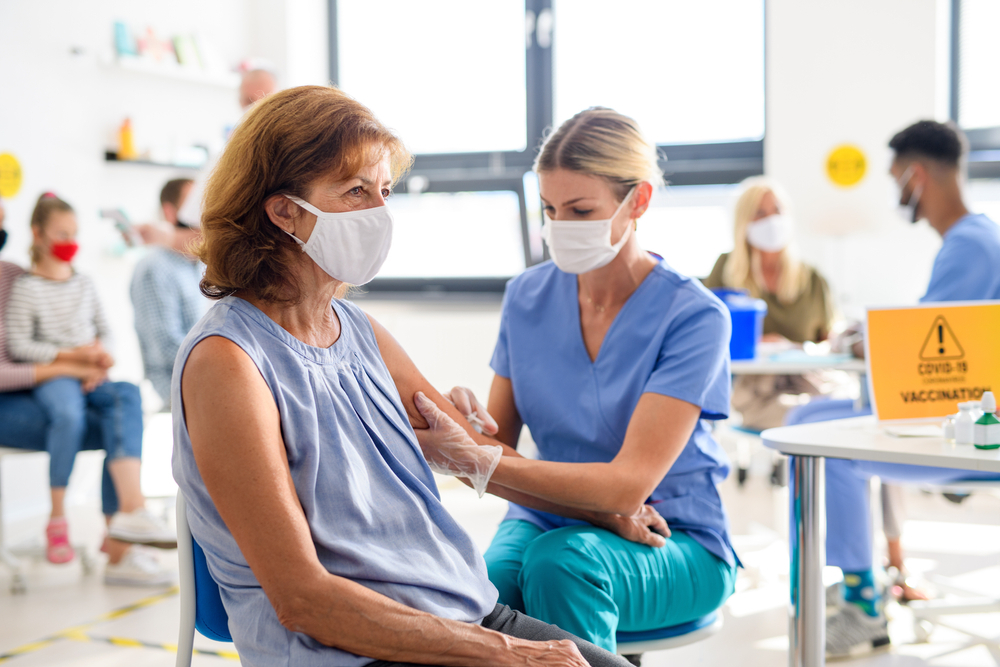 doctor administering covid vaccine to middle aged woman