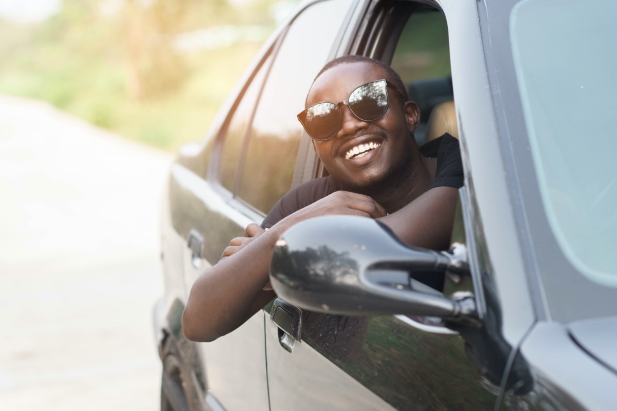 young black man in sunglasses leaning out open car window