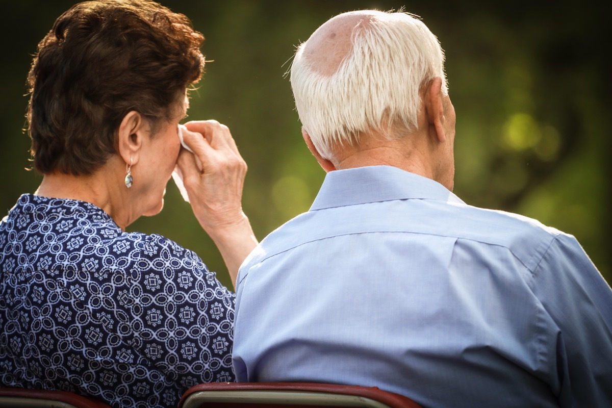 T0KC4M Elderly couple crying and watching sad or happy situation together.