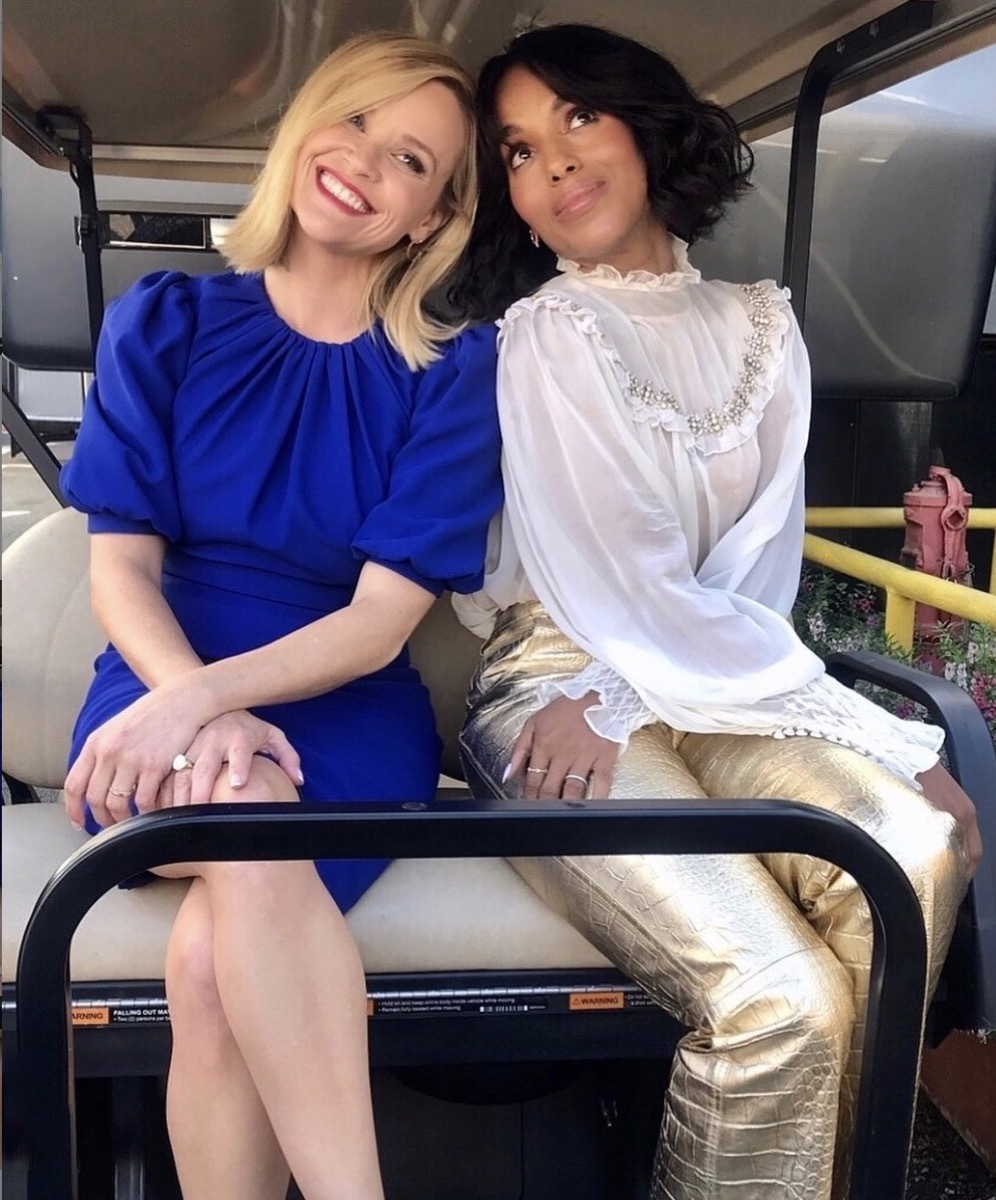 reese witherspoon in a blue dress and kerry washington in gold pants and a white top sitting in the back of a golf cart