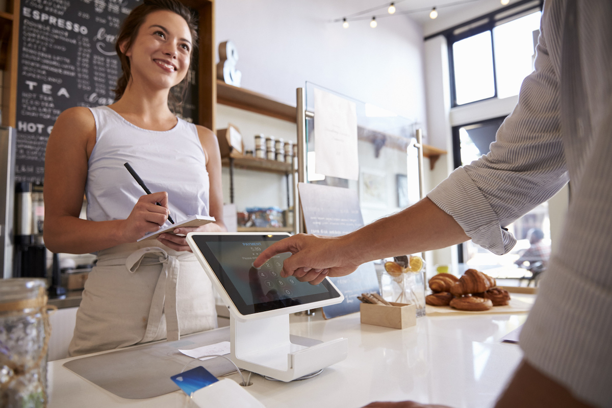 Customer using touch screen to make payment at a coffee shop