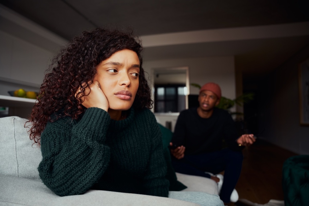 female upset with boyfriend while fighting on the sofa in modern apartment