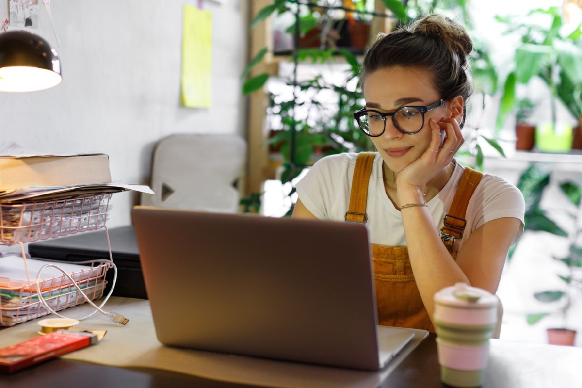 Young woman in glasses using laptop sitting at desk