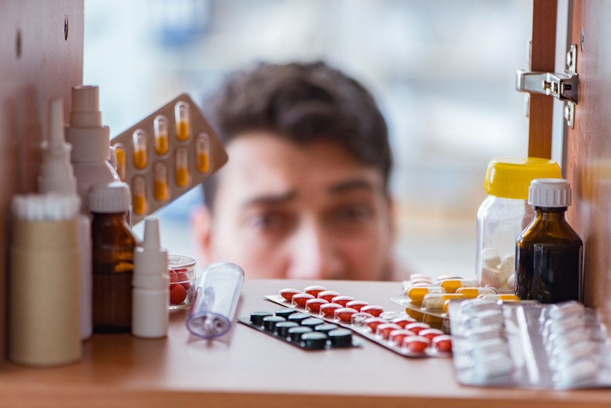 Sick ill man looking for medicines at pharmacy shelf