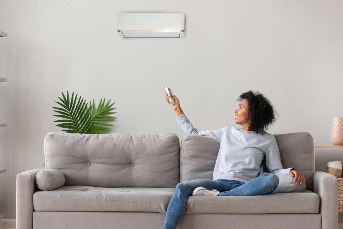 young black woman turning on mini split air conditioner