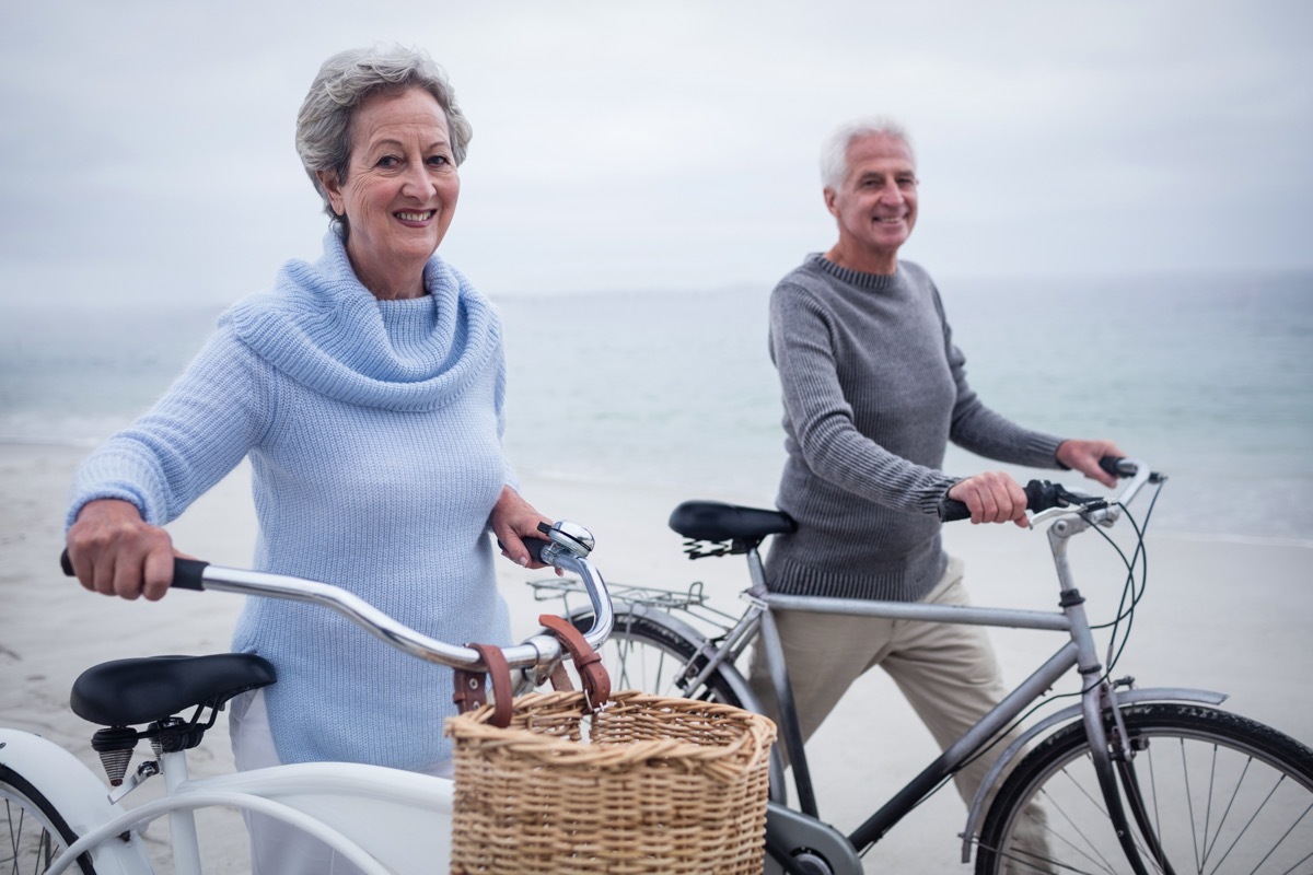 Older couple going for a bike ride on vacation near the beach