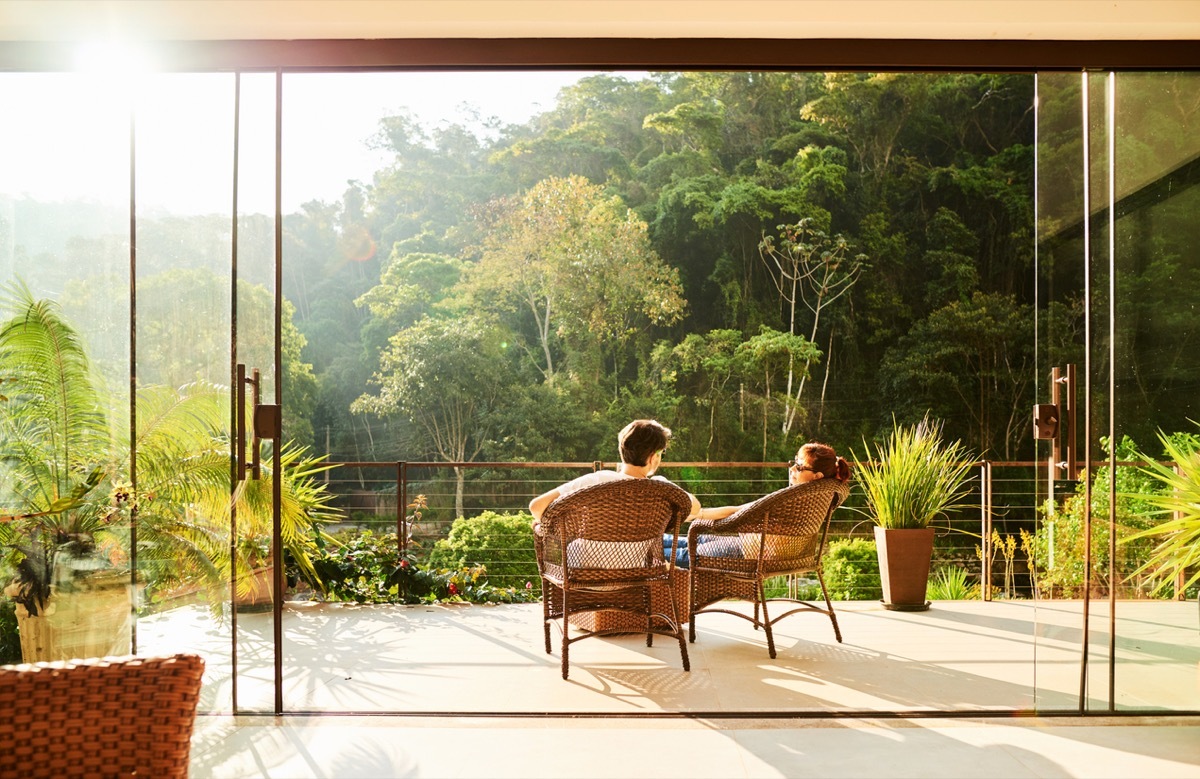 Rear view of a couple relaxing in the chairs at hotel balcony