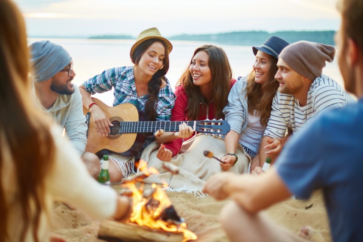 a group of men and women sing songs around a campfire