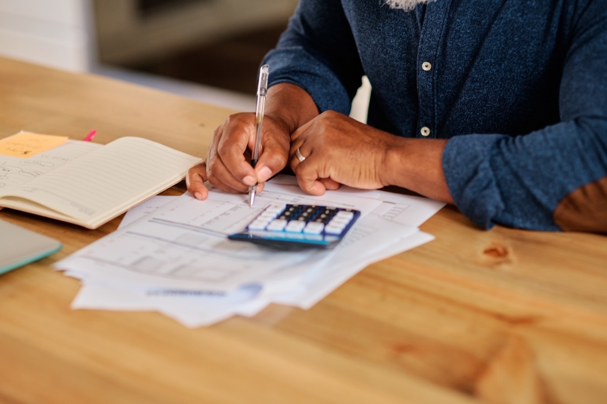 Cropped shot of an unrecognizable mature man calculating and going over his finances at home