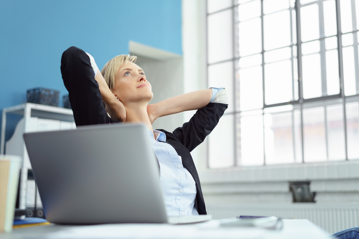 Thoughtful businesswoman taking a moment to relax leaning back in her chair staring up into the air with her hands behind her head